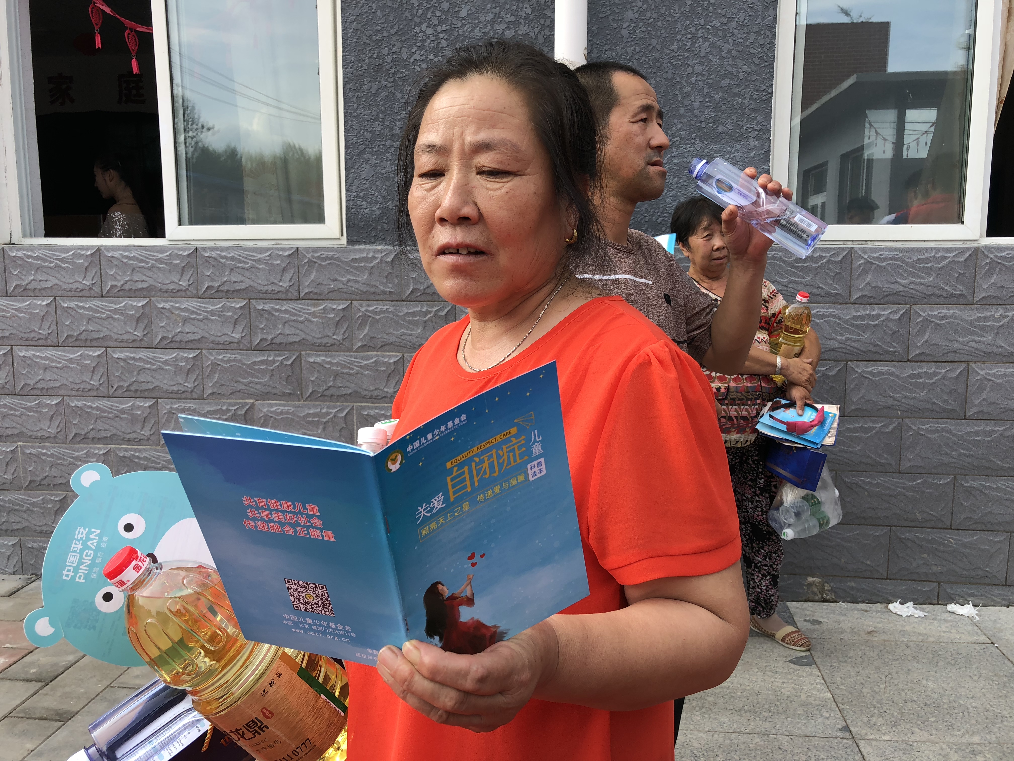 村民在活动现场认真阅读关爱自闭症儿童科普读本.jpg