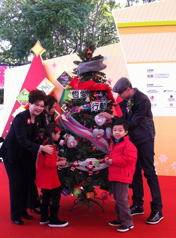 周洁冰女士与香港的小朋友将爱心挂上圣诞树，祝福孤残儿童健康成长。